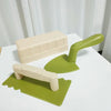 A beige sand and snow building play set featuring a shovel and brick molds on a white surface.