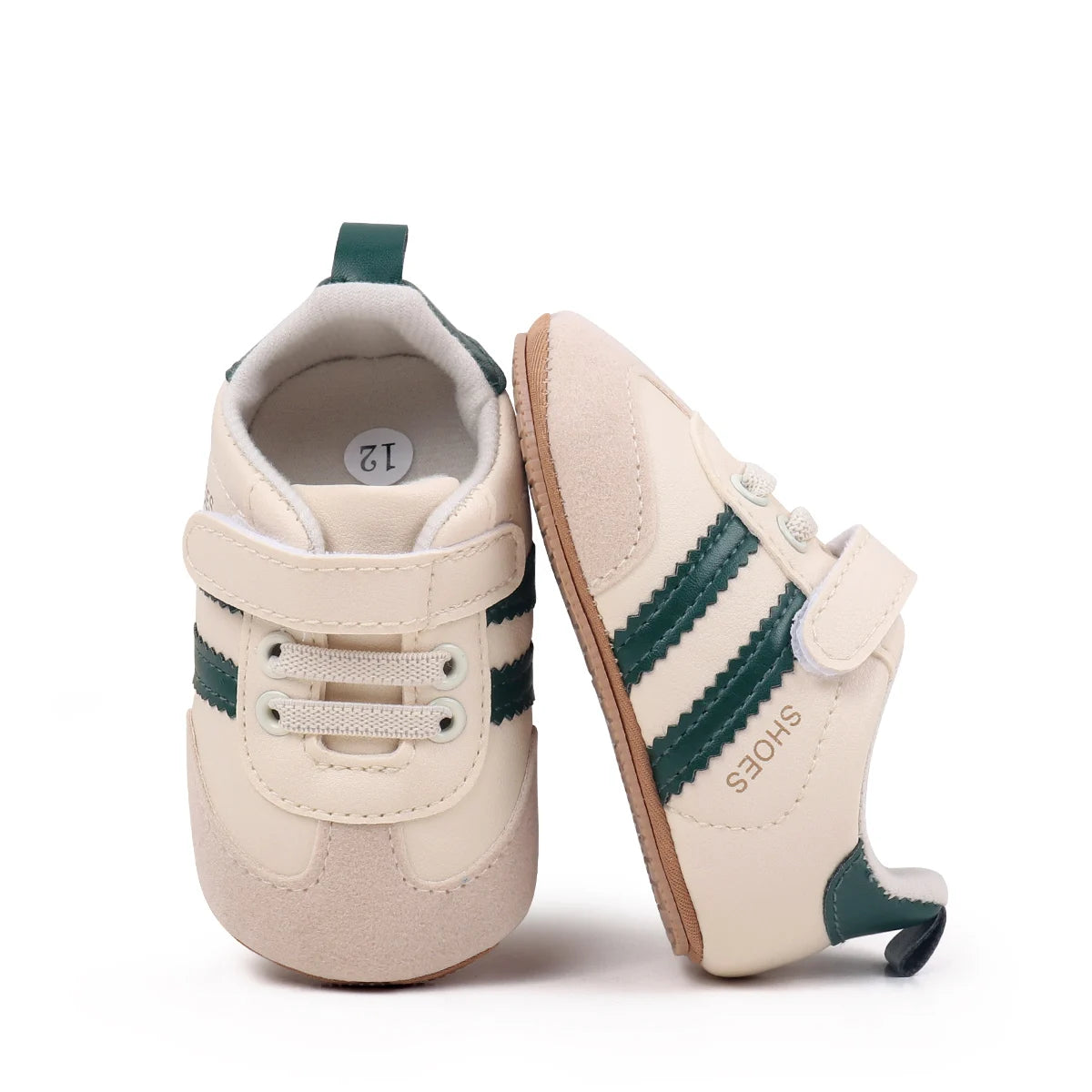A pair of beige baby first walkers soft sole shoes with green stripes and a light tan interior.