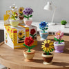 A set of colorful building block flowers in various pots and a white desk lamp on a wooden table.