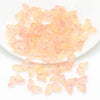 A pile of translucent pink and yellow butterfly glass beads for jewelry making