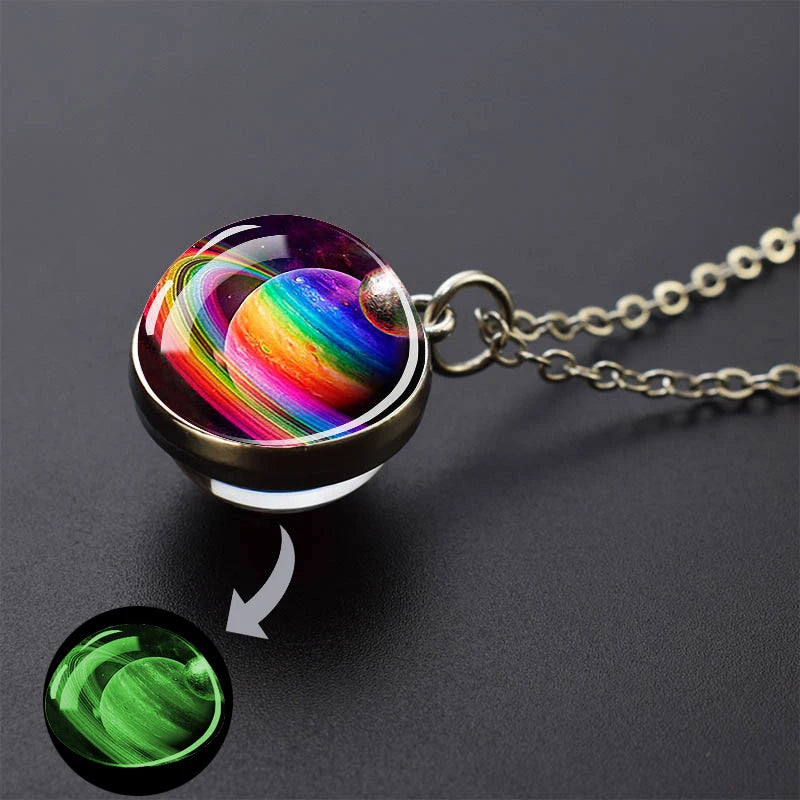 A pendant necklace featuring a glass sphere with a vibrant, colorful solar system display and a glowing green element.