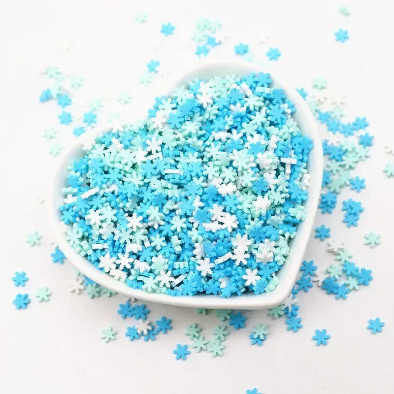 A white bowl filled with blue and white polymer clay sprinkles scattered on a white surface.