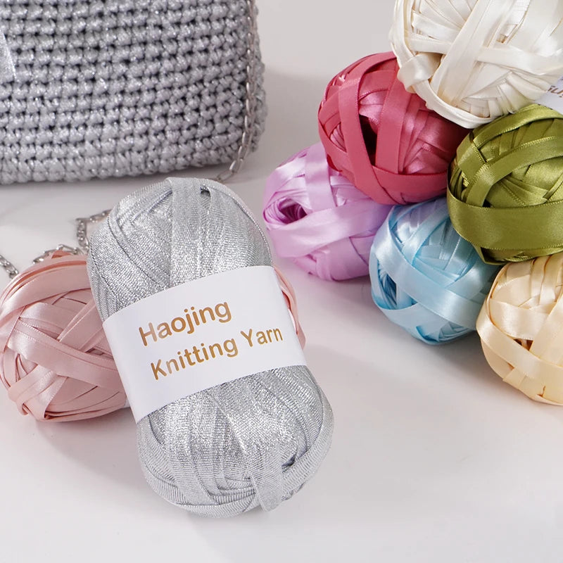 A collection of nine colored satin ribbon yarn spools, including pink, purple, blue, green, and gold tones.