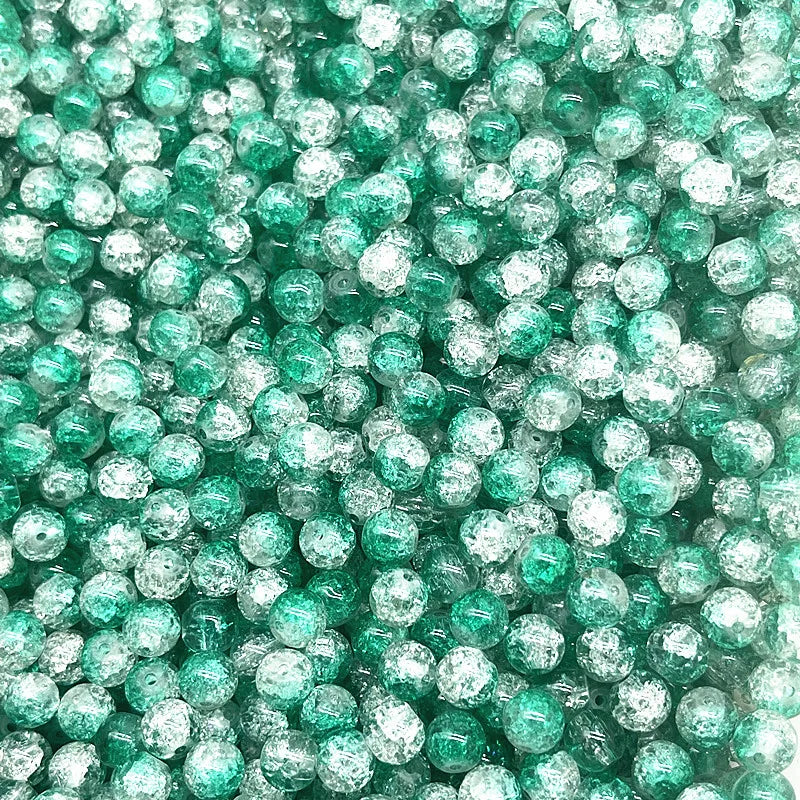A close-up view of small, round, green glass crackle beads for jewelry making.