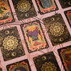 A close-up view of a mini gold foil tarot card deck featuring various cards with intricate designs.