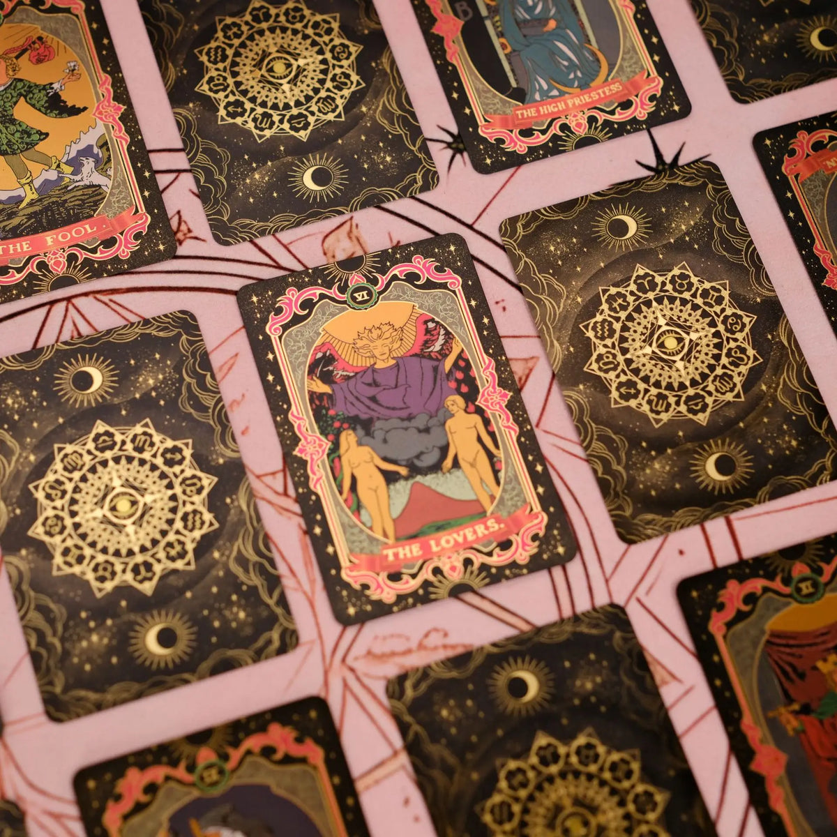 A close-up view of a mini gold foil tarot card deck featuring various cards with intricate designs.