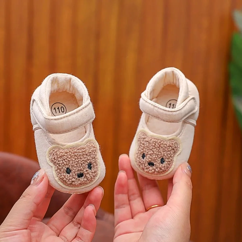 Pair of beige soft sole sandals shaped like bears for a baby's first steps