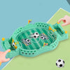 A green tabletop foosball game is shown with a soccer ball and goal nets, being handled by a hand on a light green surface.