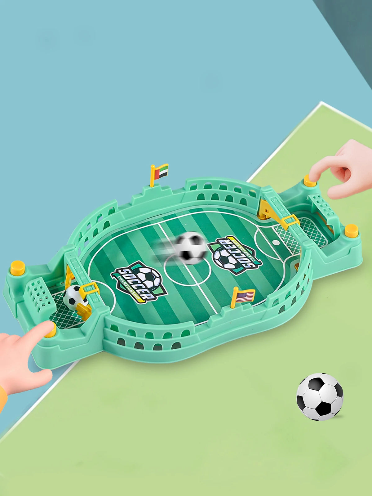 A green tabletop foosball game is shown with a soccer ball and goal nets, being handled by a hand on a light green surface.