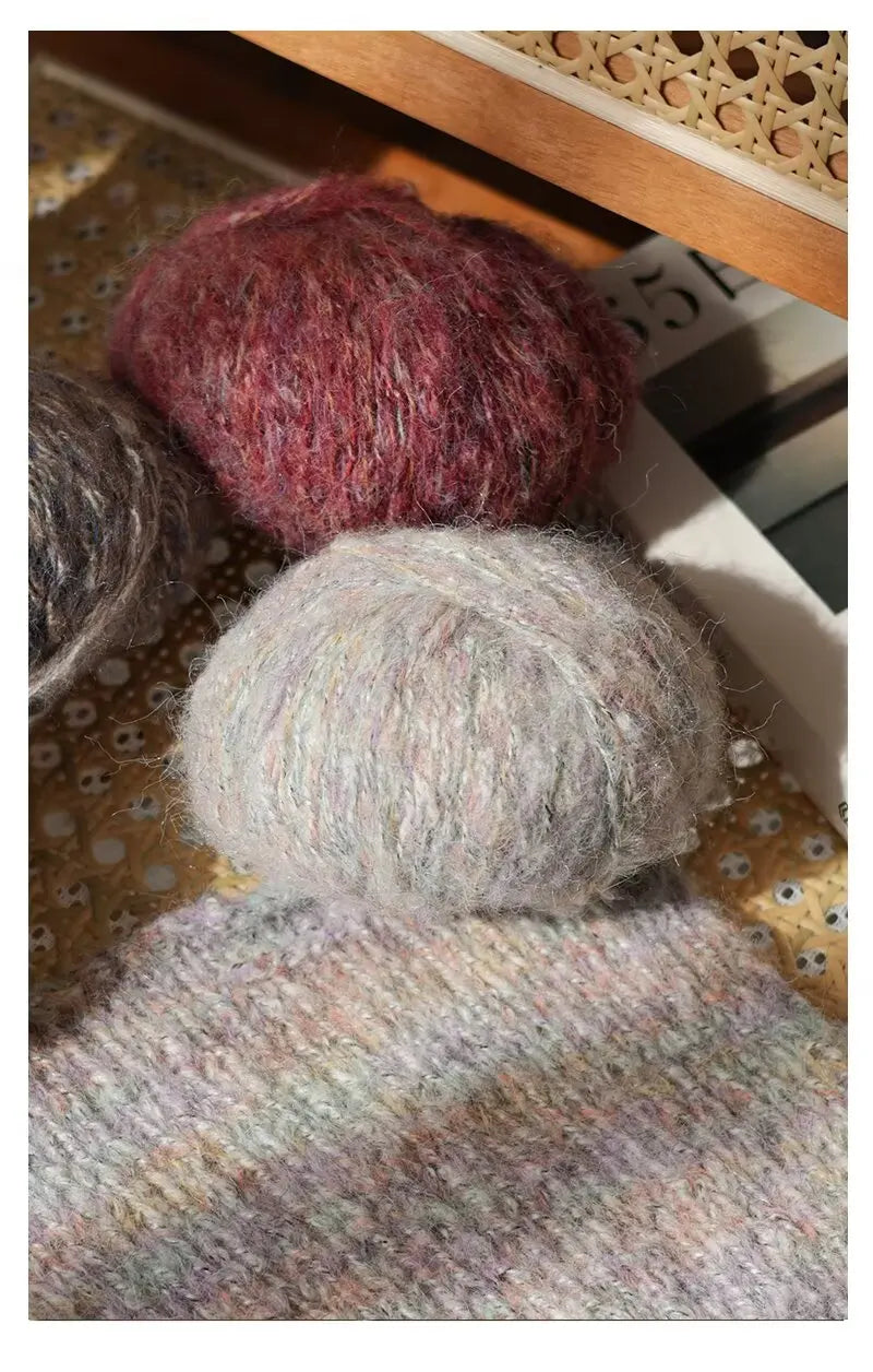 Two balls of soft alpaca blend yarn, one deep reddish-pink and one light gray, displayed next to a knitted swatch.