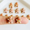 A set of thirty small gingerbread man resin nail art charms arranged on a white surface.
