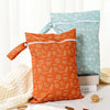 Two reusable waterproof baby wet bags in orange and mint green colors resting on a white surface.