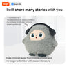 A gray plush robot with large blue eyes sits on a white surface.