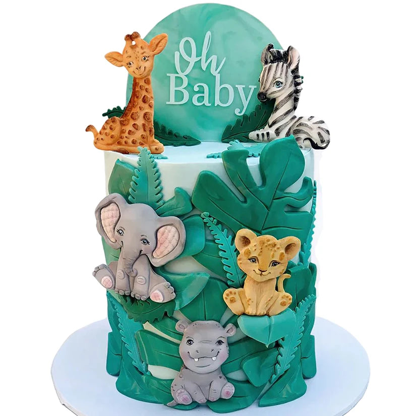 A green cake decorated with elephant silicone baking molds featuring a giraffe, zebra, and lion cub.