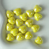 A pile of bright yellow heart-shaped ceramic beads for jewelry making.