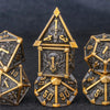A set of seven metal dice featuring skulls and dragons in gold and dark metal tones.