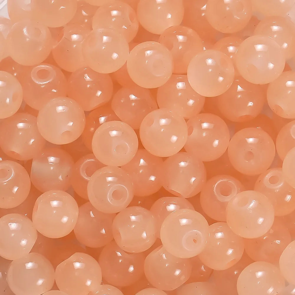 A close-up view of small, round, translucent orange glass beads for DIY jewelry making.