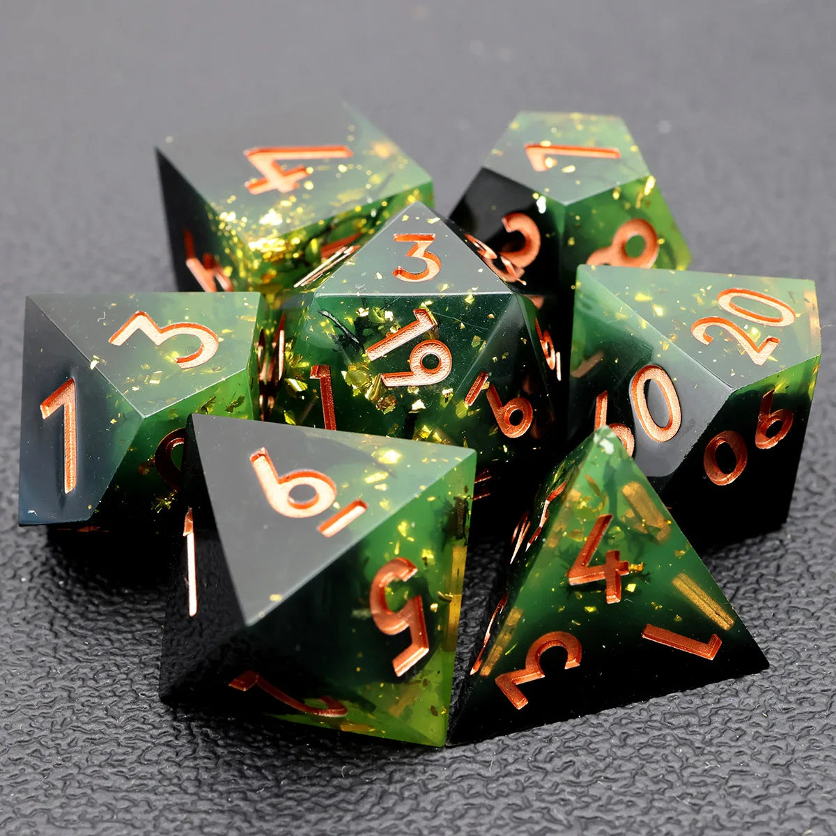 A pile of seven green resin polyhedral dice with gold markings resting on a dark surface.