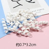 A pile of white polymer clay marshmallow charms is displayed on a pink surface.