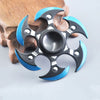 A metal fidget spinner with a rainbow finish is shown resting on a wooden surface.