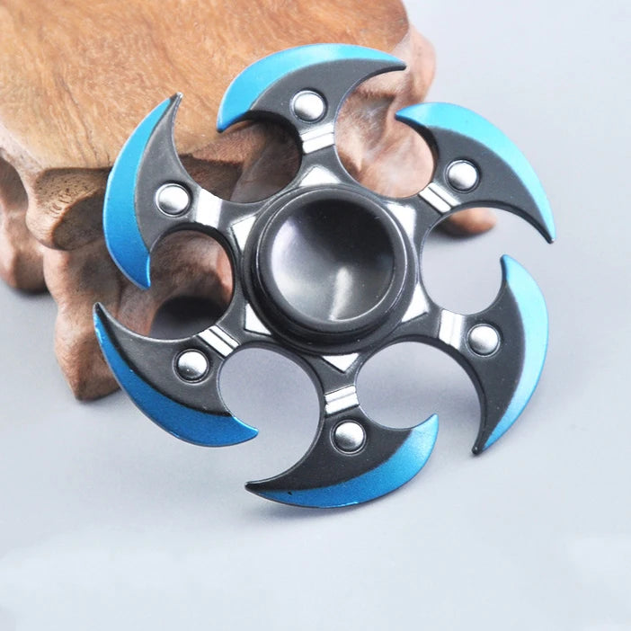 A metal fidget spinner with a rainbow finish is shown resting on a wooden surface.