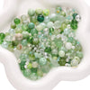 A pile of multicolored green and clear glass beads for jewelry making