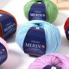 A collection of YEDAN MERINO wool thread in various colors including green, brown, blue, and pink yarn skeins.