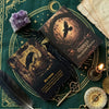 A dark velvet green cloth features an open deck of Raven's Awakening Oracle Cards with gold accents and a brass key.