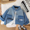 A blue and white striped denim jacket with chest pockets lying on a white fabric background.