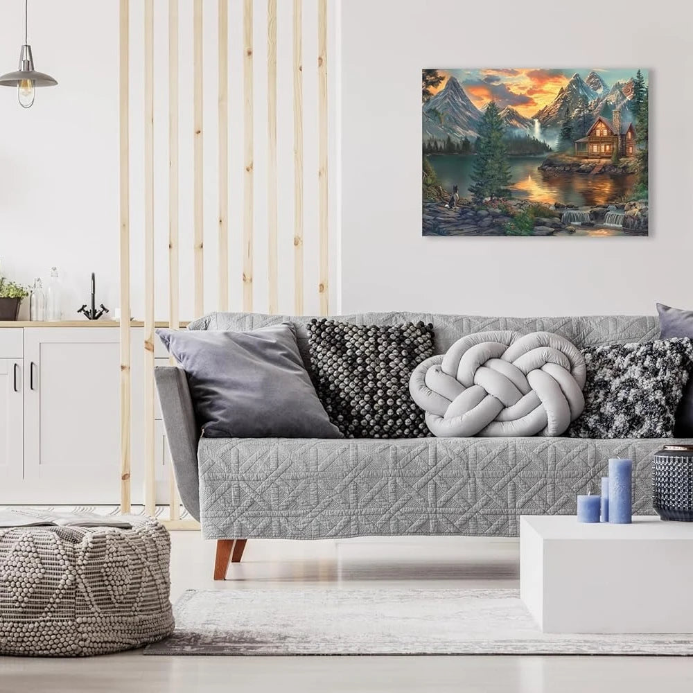 A gray sofa in a living room with a painting of a mountain cabin lake view above it.