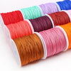 A collection of colorful macrame cord rolls in various shades of red, pink, orange, and blue for jewelry making and crafts.