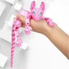 A hand is holding a pink articulated 3D printed sphynx cat figurine with large eyes and long pink limbs.