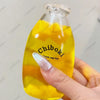 A hand holds a clear bottle filled with yellow liquid, labeled Chiboki, which is a fruit bottle stress ball toy.