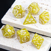 A set of yellow marble dragon pattern polyhedral dice resting on a white textured surface.