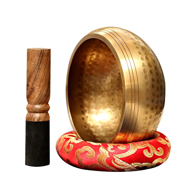 Handmade copper singing bowl with a mallet resting on a red fabric base