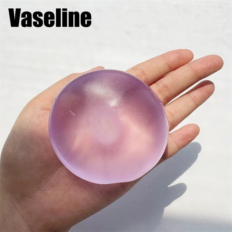 A hand holds a translucent pink silicone fidget ball for stress relief and focus.