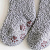 A pair of gray, fluffy fleece socks with small paw prints on the sole.