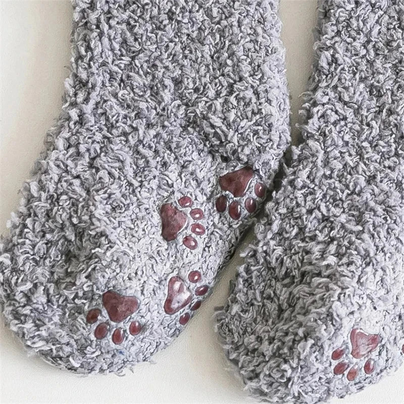 A pair of gray, fluffy fleece socks with small paw prints on the sole.