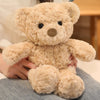 A light beige twisted teddy bear plush toy is being held by a person.