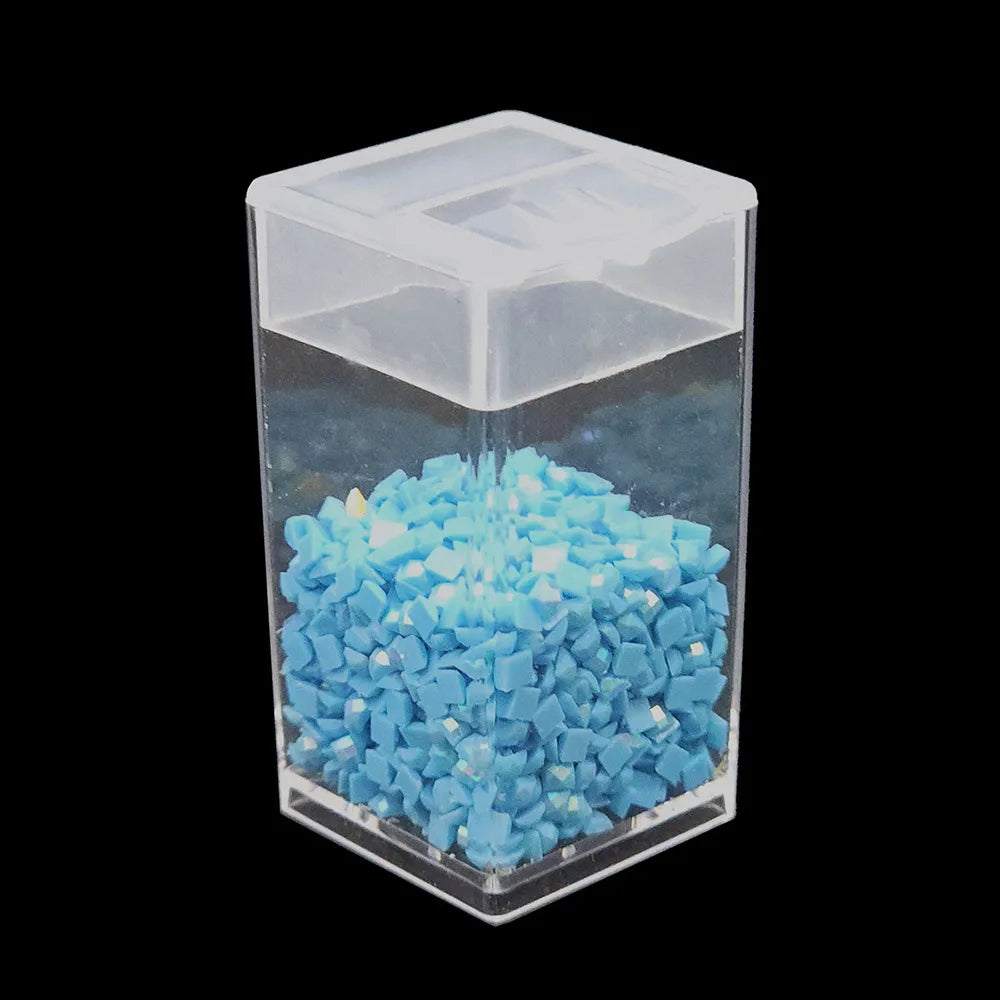 A clear storage box filled with small, light blue diamond painting tiles and organized by trays.