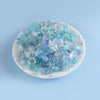 A pile of assorted light blue and teal acrylic beads for DIY jewelry making