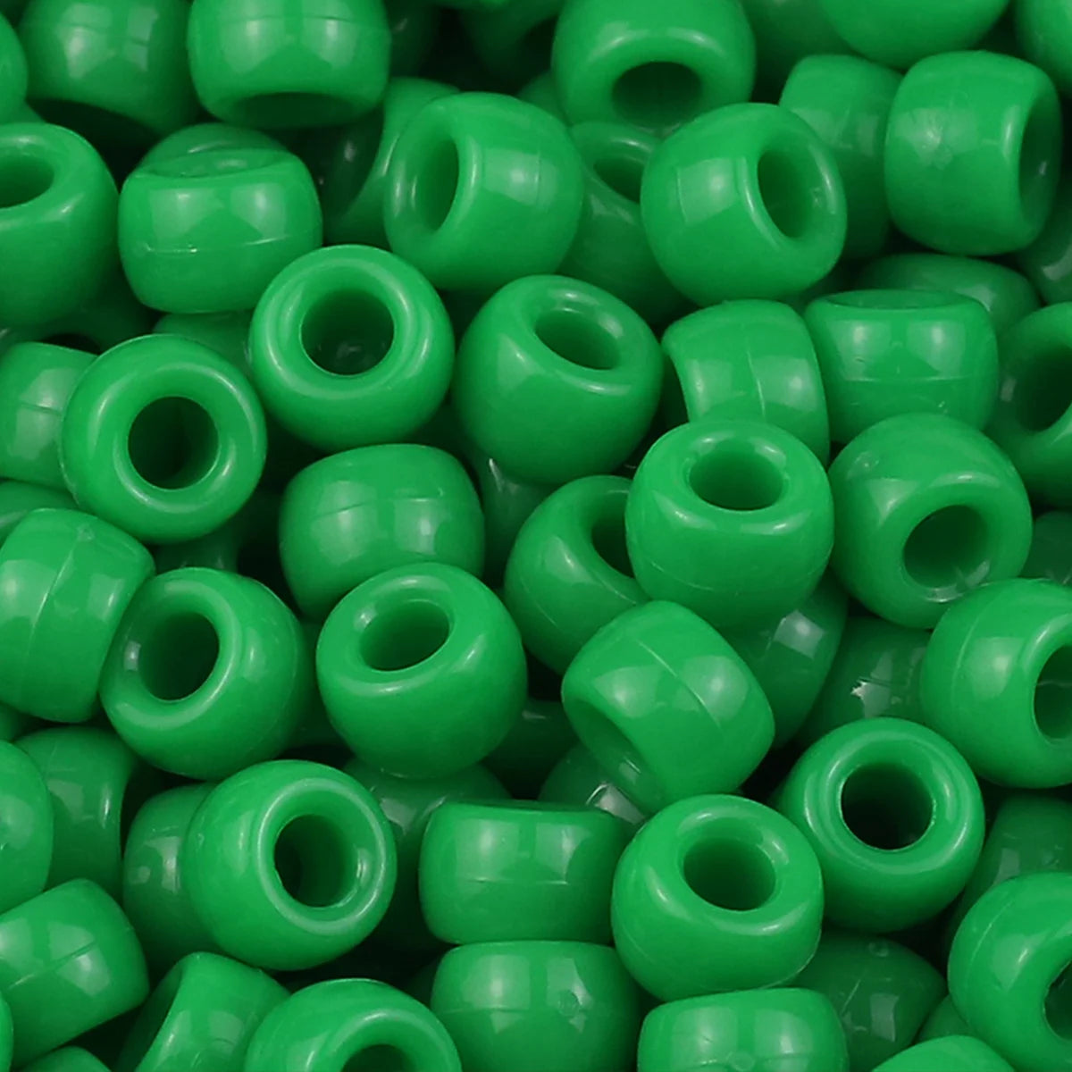 A close-up view of small, solid green pony beads used for jewelry making and craft projects.