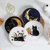 A set of embroidery kits featuring black cats and crescent moons on round fabric pieces with yellow and green floral accents.