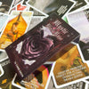 A dark purple box of the Mystic Black Rose Oracle Deck lying on top of several other tarot or oracle cards.