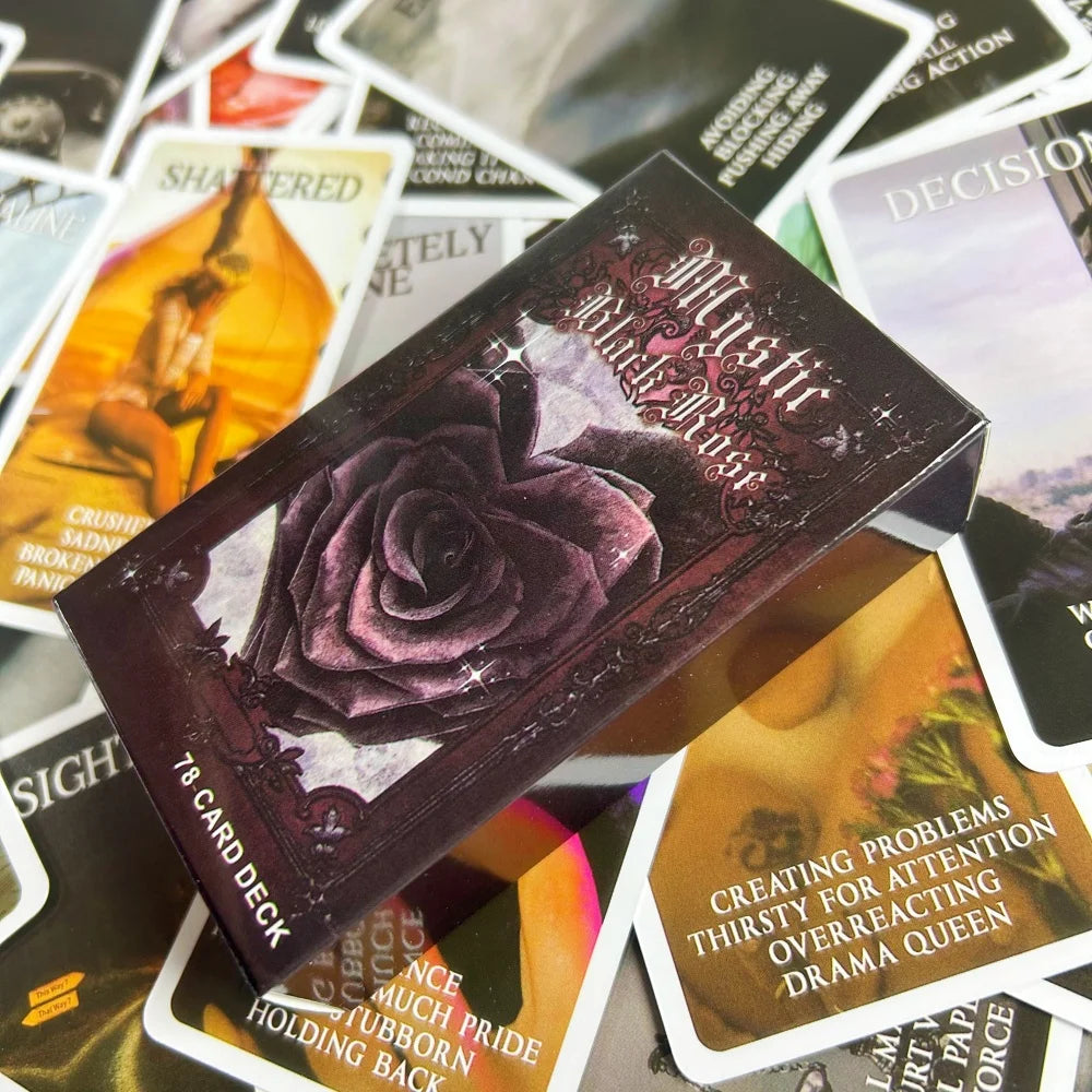 A dark purple box of the Mystic Black Rose Oracle Deck lying on top of several other tarot or oracle cards.
