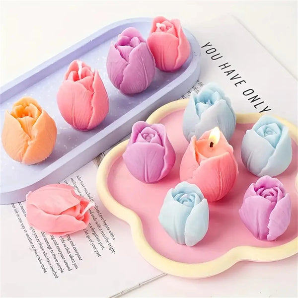 A collection of pink and purple silicone tulip flower molds for candle and soap making displayed on a light wooden tray.