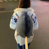 A person is holding an adorable mouse plush backpack with pink ears and a light-colored coat.