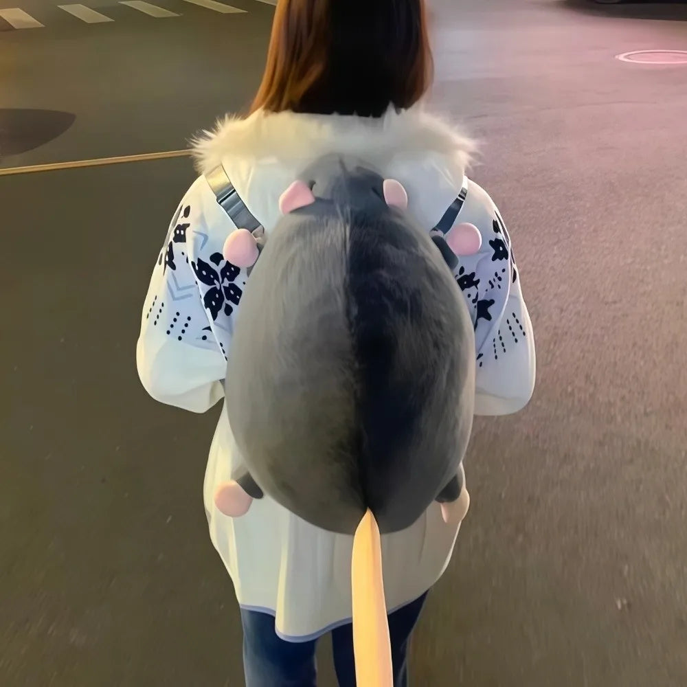 A person is holding an adorable mouse plush backpack with pink ears and a light-colored coat.