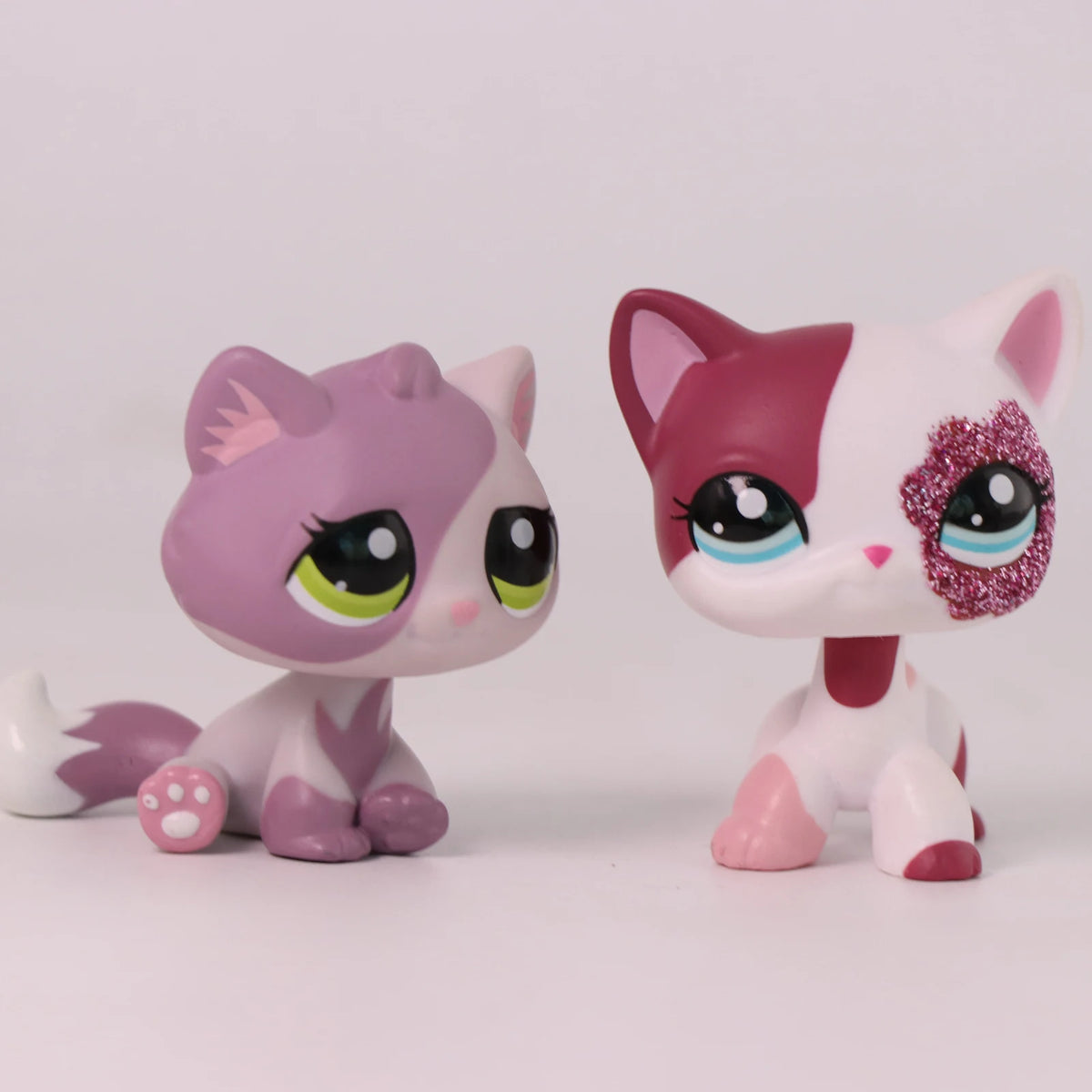 A pink and white shorthair cat bobble head figurine with large eyes and pink accents.