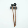 A pair of wooden handpan drum mallets with black silicone tips resting on a white background.
